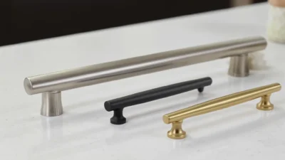 Comparison of brushed nickel, matte black, and brass cabinet pulls on a white kitchen cabinet.
