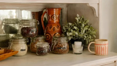 Stylish open kitchen shelf with ceramic canisters, wooden cutting boards, and potted herbs for display.