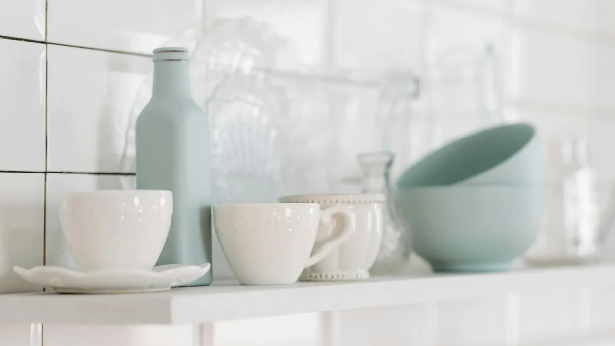 Stylish kitchen open shelves with balanced arrangement of cookbooks, plants, and white dishes