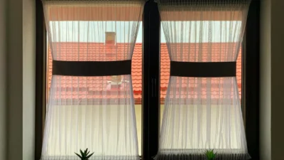 Modern kitchen with white Roman shades and a vase of fresh flowers on the windowsill.