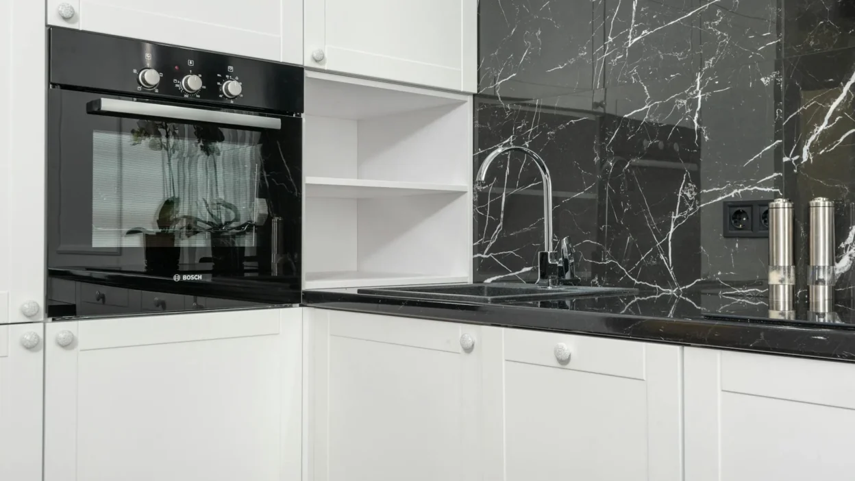 Modern kitchen with mixed metal finishes: brass faucet, stainless steel appliances, and matte black hardware.
