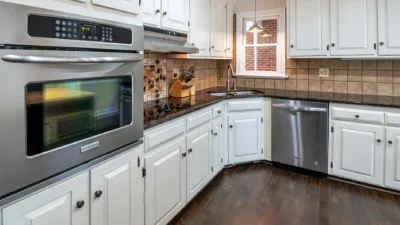 Side-by-side comparison of kitchen cabinets with a fresh white paint finish and original stained wood finish.