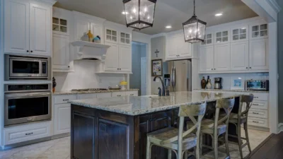 Modern kitchen with cohesive design featuring white cabinets, brass hardware, and a marble subway tile backsplash.
